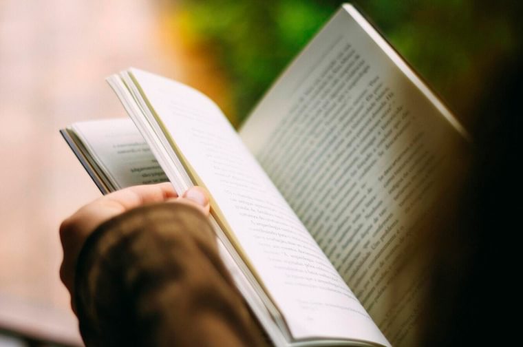 A person is holding and flicking through the pages of an open book