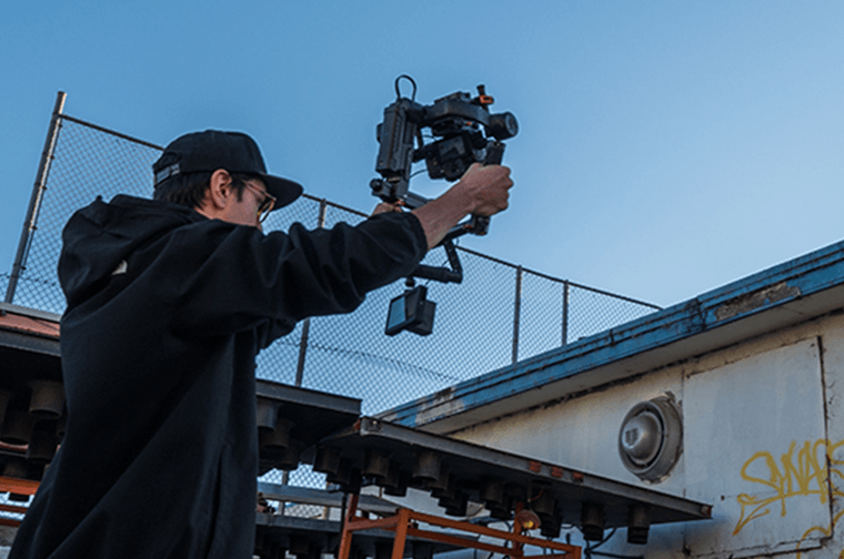 A person is outside, holding a camera above their head filming