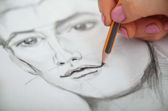 A close up drawing of a face, with someone using a pencil to shade the lips