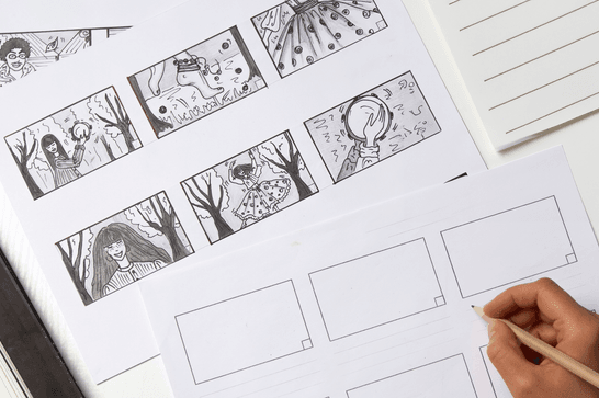 A person is drawing a story onto a storyboard with pencil on paper