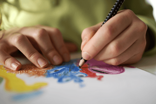 A young person drawing on a piece of paper