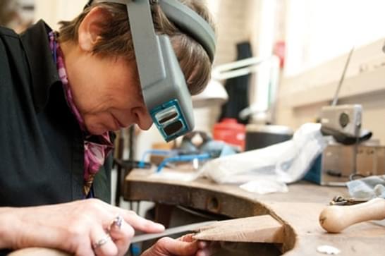 Woman solders metal in jewellery studio