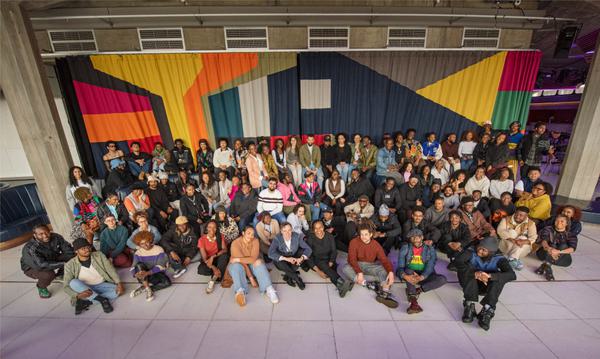 Black and Black Mixed Heritage artists sit in Southbank centre with tutors, colourful background behind