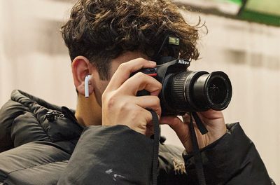 A person is holding a black camera to their face, taking a picture
