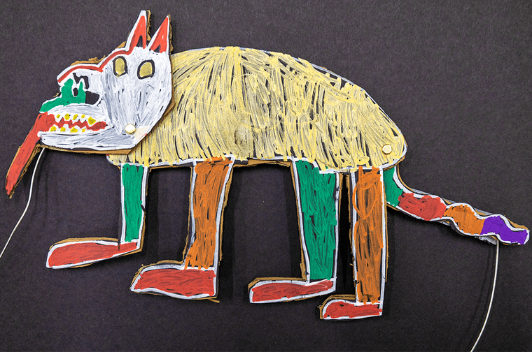 Handmade multi coloured puppet for a mythical animal. There are strings tied on the face and tail to make it move.