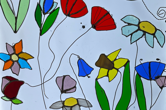 A range of spring flowers made from glass, sitting on top of a light board