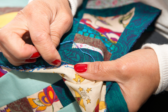 a woman is stitching squares of fabric together
