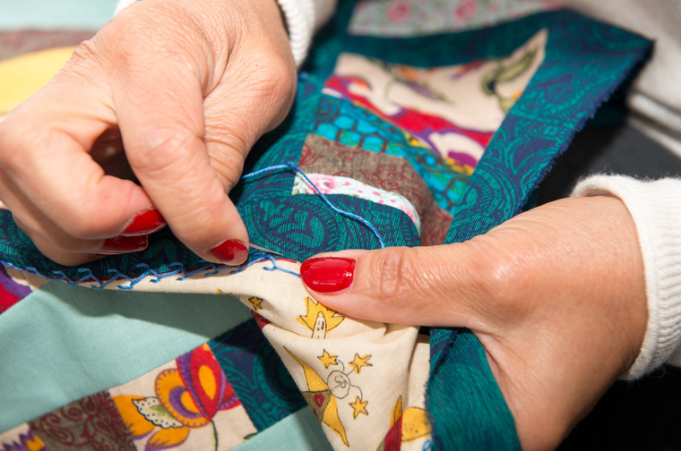 a woman is stitching squares of fabric together