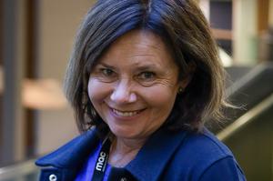 A woman with short brown hair, smiling, wearing a blue jacket