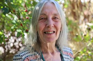 A woman with long grey hair is smiling at the camera