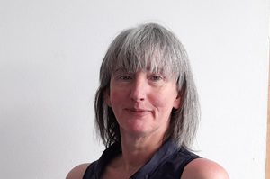 Ronnie has shoulder-length grey hair and a fringe.