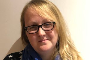 Sian has long blonde hair and is wearing glasses and a black and white star top