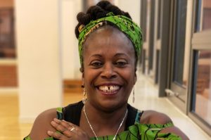 Sandra is wearing her dark brown hair tied up with a green headband, matching her top.