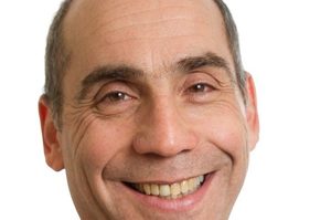 Jon is against a plain white background. Jon has short brown hair and is smiling at the camera.