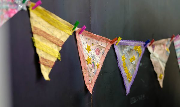 Image shows colourful triangular bunting being displayed against a plain black background.