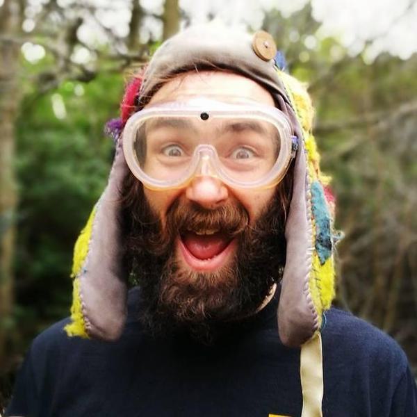 Martin has a medium length brown beard, and has his mouth open smiling whilst wearing goggles and a woolly hat.