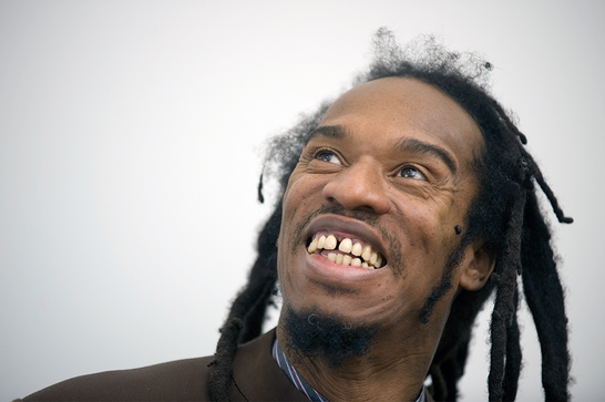 Benjamin Zephaniah smiles and looks off to the left.