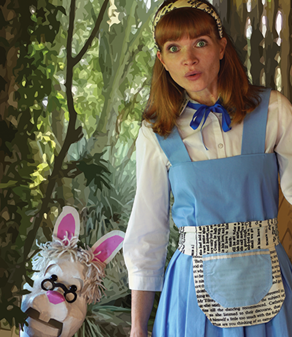 A women in a blue apron and wearing a hair band stands next to a rabbit puppet with glasses.