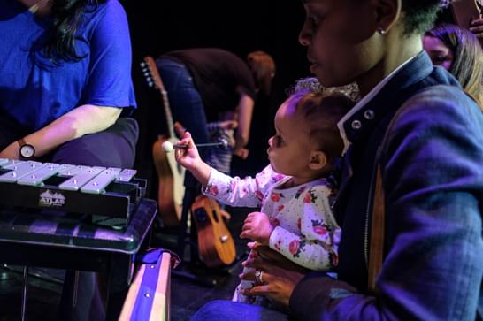 Parent and baby play with instruments in music session