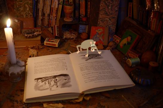 A grey cartoon mouse sits on a book that has an illustration of an old ship on it. A lit candle sits next to the book.