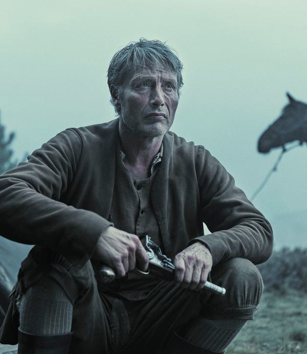 A grey-haired man (Mads Mikkelsen) in 18th century dress crouches by a tent holding a gun. A horse is tethered in the background.