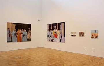 Large paintings hung on a white wall in a gallery