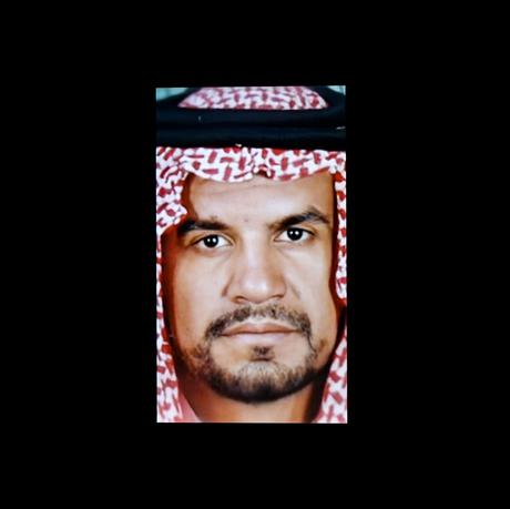 Man wearing male hijab, close-up colour photo of his face with a black background