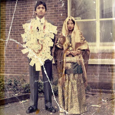 Man and woman just married outside register office. Man is covered in bank notes in a Pakistani wedding tradition.