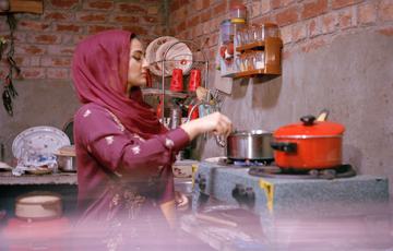 Woman in purple saree and hijab in a Pakistani kitchen