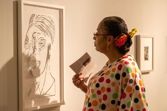 Woman in spotty top looks at artwork in a gallery