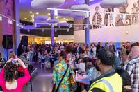 A crowd gathers in KILN, looking at a stage with a speaker on it.