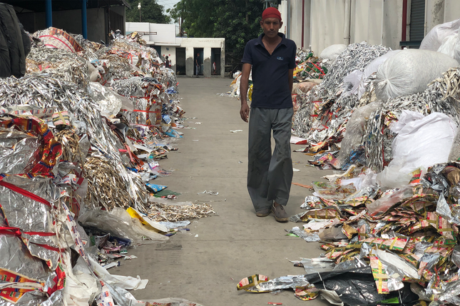 A man walks down a path lined with rubbish on either side