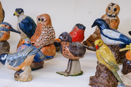 A variety of handmade ceramic birds, sat against a white background