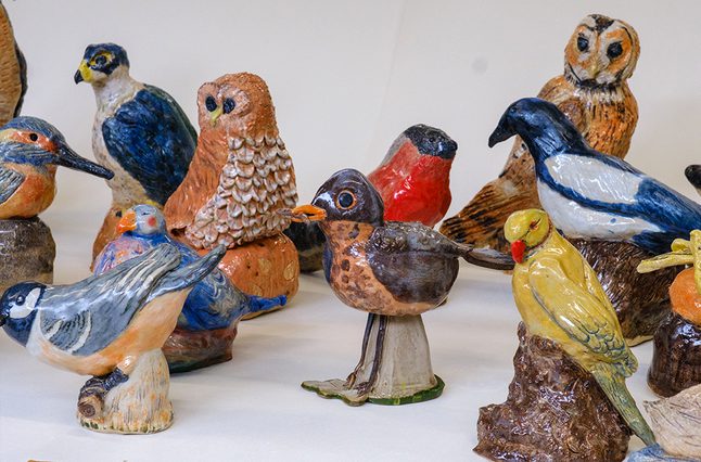 A variety of handmade ceramic birds, sat against a white background