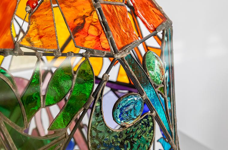 a lamp, made from orange, green and blue glass pieces that have been soldered together