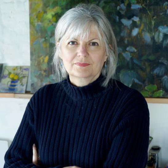 Helen is wearing a black turtle neck jumper and has her grey hair tied in a pony tail with a fringe.