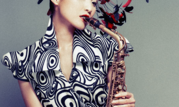 Megumi wears a black and white dress and plays a saxophone.